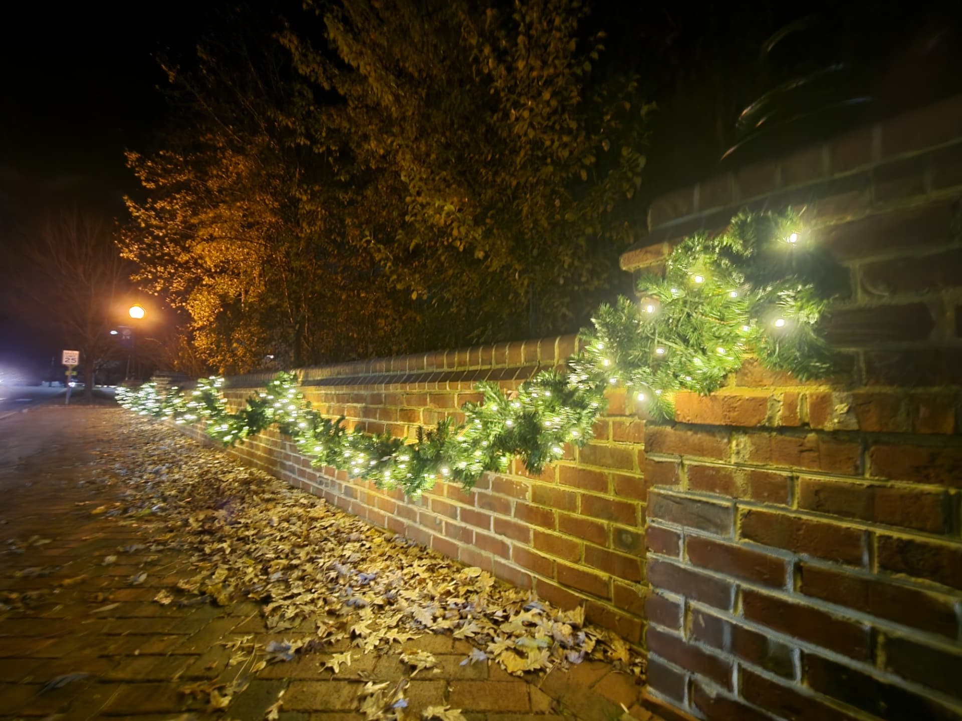 Brick wall lined with lighted evergreen garland