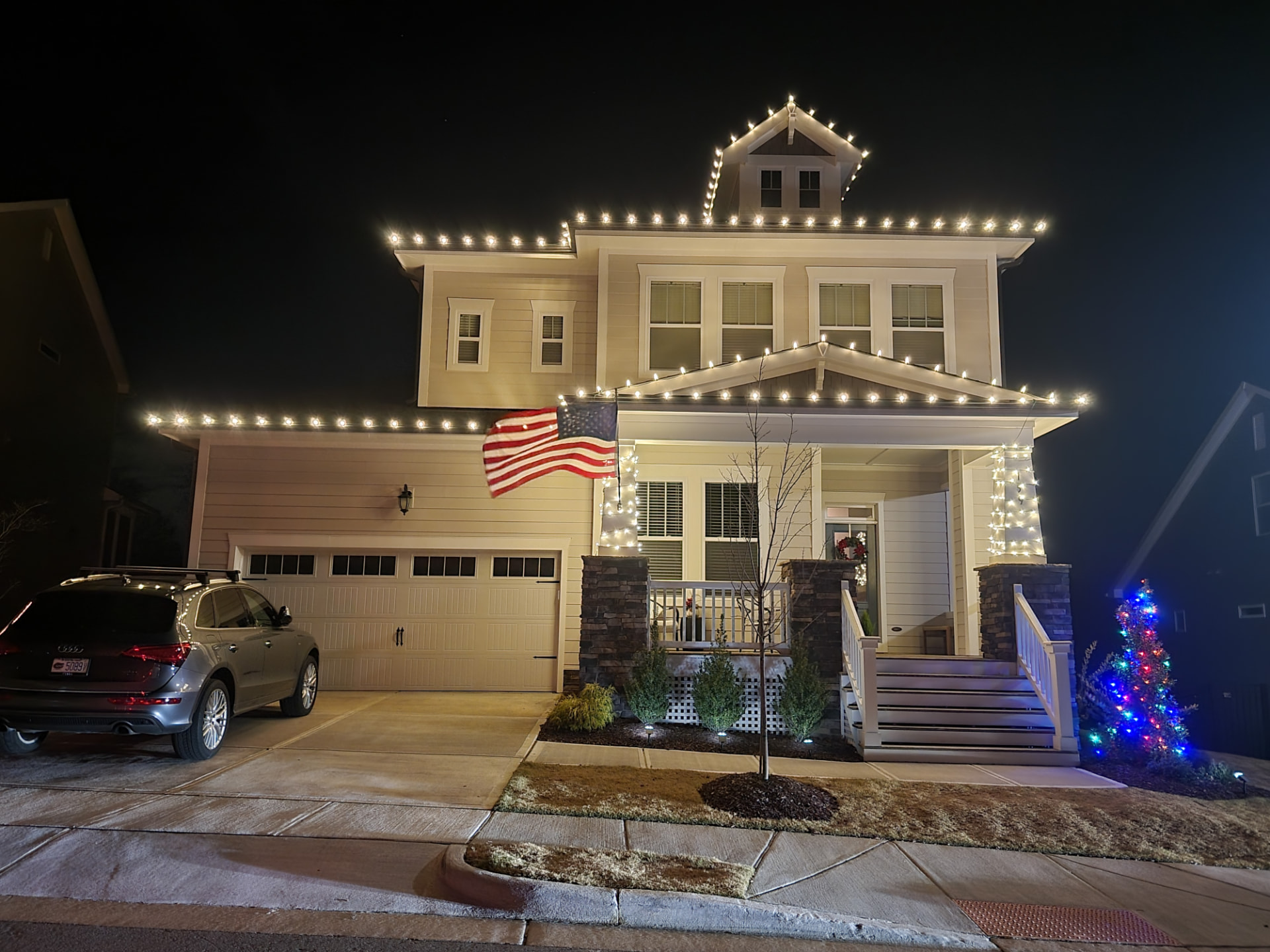Warm white roofline and porch lighting with a lit tree