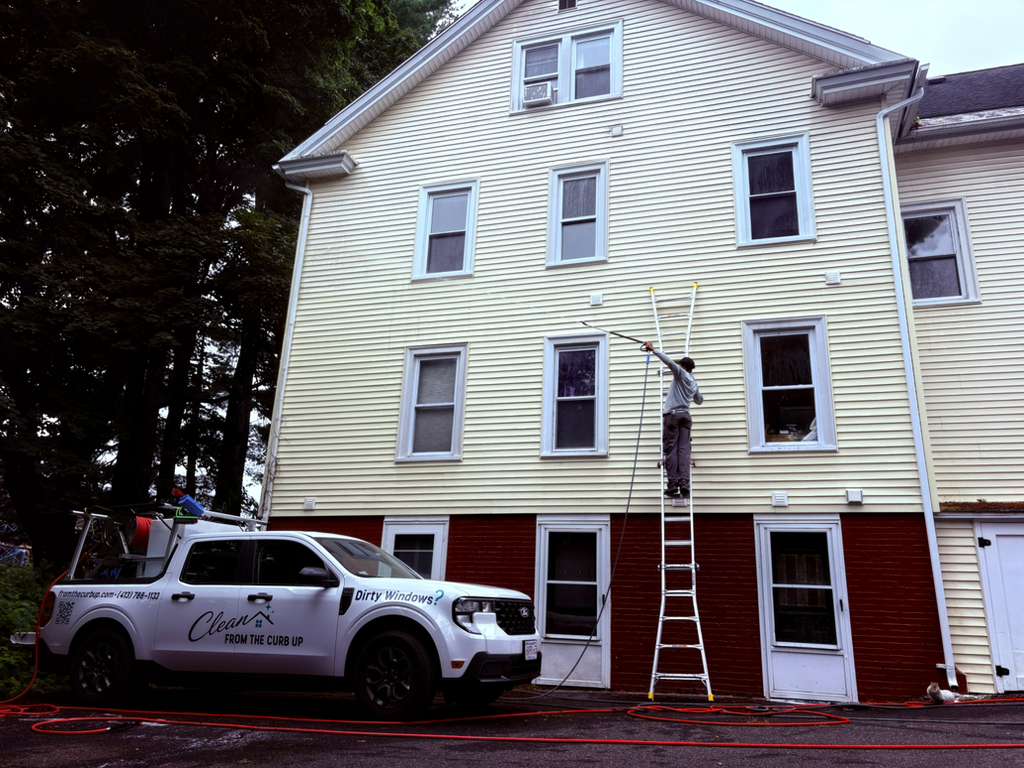 Commercial window cleaning with water-fed pole from a ladder