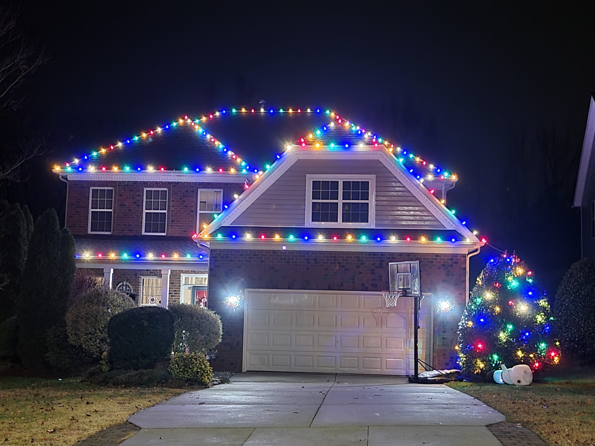 Multicolor C9 roofline lights across a two-story home and garage